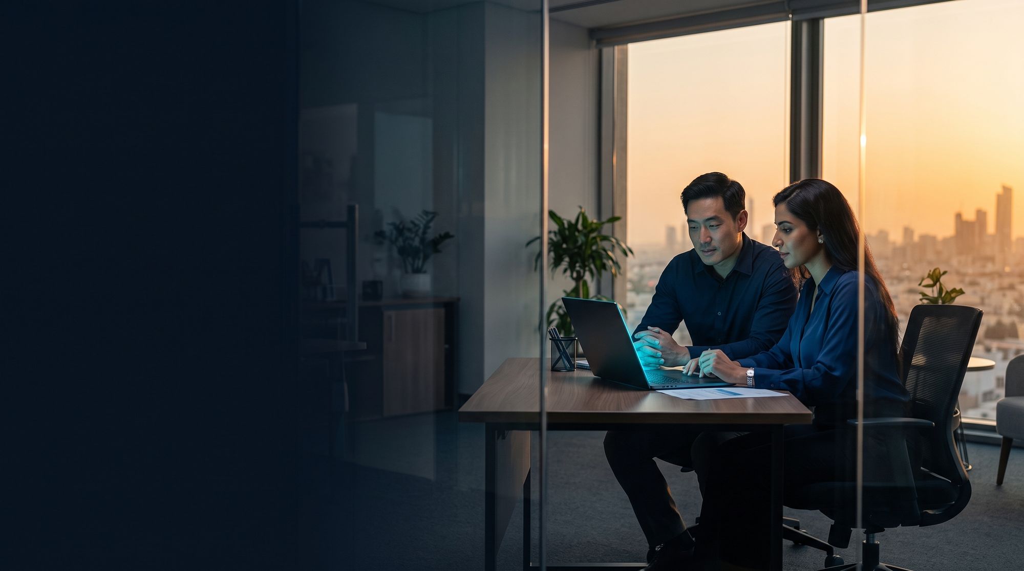 Two colleagues working at a laptop in an office